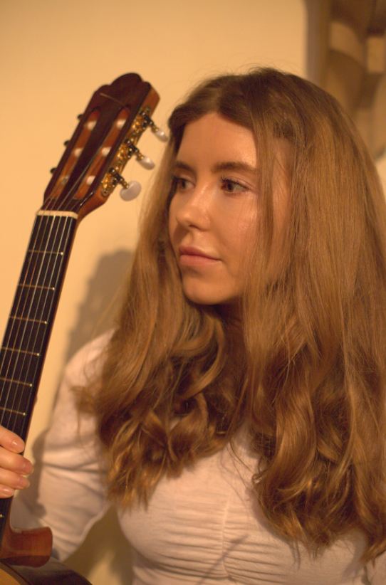 Portrait of India Falconer beside the headstock of her classical guitar