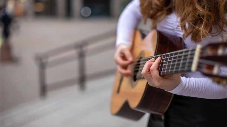 Close-up of the hands of India Falconer playing fingerstyle guitar outdoors