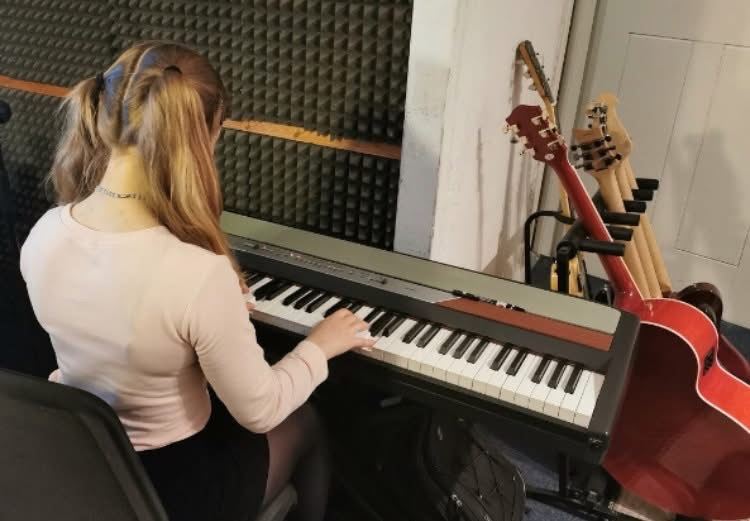 India Falconer playing a digital piano in a music teaching studio
